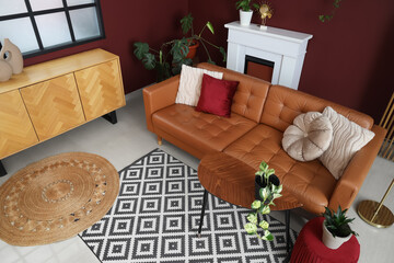 Interior of modern living room with cozy brown sofa, coffee table, ottoman and fireplace