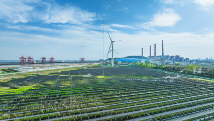 Renewable energy landscape with a solar panel farm and wind turbine coexisting with a traditional power plant.