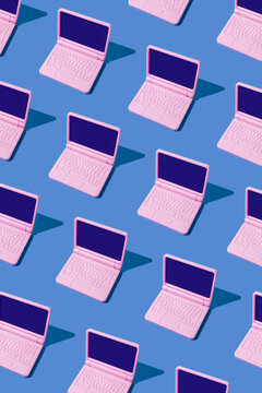 Pink laptops arranged in seamless pattern on blue background
