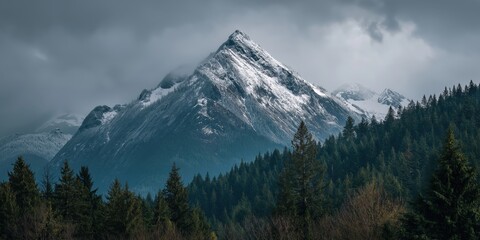 Obraz premium Majestic Mountain Peak: A breathtaking panorama of a towering mountain peak shrouded in misty clouds, showcasing the raw, untouched beauty of the natural landscape.