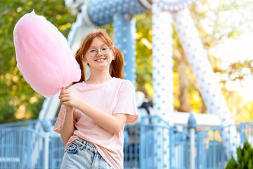 Teen girl with cotton candy in amusement park