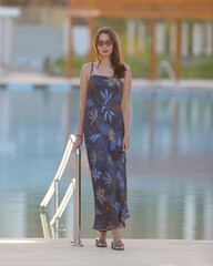 portrait of tall slim brunette woman in dark fashionable long dress at resort