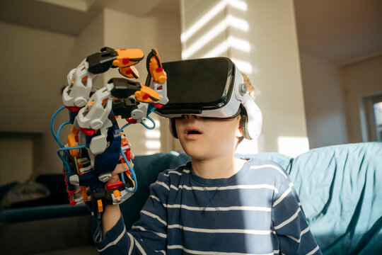 Boy looking at robotic arm through VR glasses at home