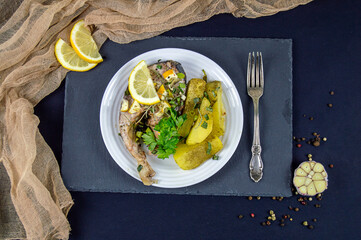 chicken leg and baked potato served with lemon and spices
