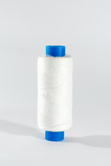 A white spool of thread with a blue cylinder, isolated on a clean white background, a symbolic...