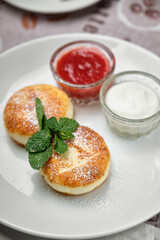 Delicious syrniki with toppings on a white plate