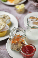 Breakfast table setting with granola, milk, and jam