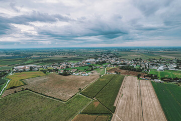 Cultivated fields and rural village under cloudy sky in po valley, italy
