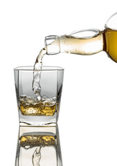 Pouring whiskey from a bottle into a glass on a white background.