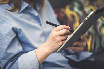 Obraz premium Digital art creation. Close-up of female hands using stylus on tablet. Artist at work, digital pen