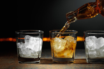Whiskey is poured into a glass with ice.