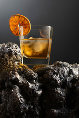 Old fashioned cocktail with ice and dried orange slice.