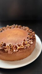 Chocolate cake decorated with walnut on white plate, black background