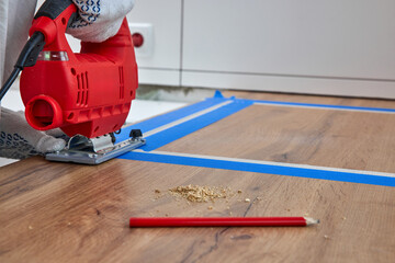 repairman using electric jigsaw and cutting hole for the sink in the kitchen countertops, close-up