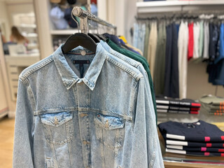 A photo of a clothing store displaying denim jackets and other garments on hangers.