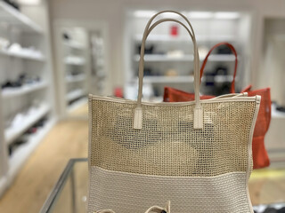 A photograph showing a beige woven handbag displayed in a store environment.
