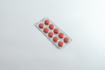 A blister pack of ten red pills, isolated on a clean white background, symbolizing medicine,...