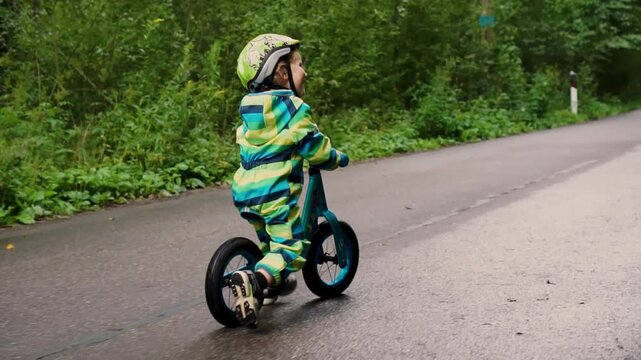 Cheerful young child enjoying balance bike ride with safety gear, developing motor skills during active family recreation time.
