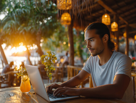 Freelancer working remotely on laptop at beach cafe during sunset