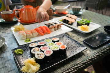 Colorful assortment of premium sushi including salmon, tuna and eel rolls, showcasing family dining experience in authentic setting.