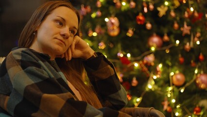 Woman in Checkered Shirt Sitting on Indoor Bench and Admiring Decorated Christmas Tree with Presents and Lights, Full Shot, Holiday Spirit Concept