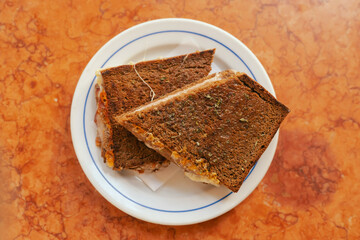 Traditional Portuguese fast food toast with bacon and cheese on a plate. Solo tourism and travel.