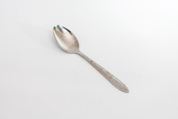 A worn metal spoon with a decorative handle, isolated on a clean white background, symbolizing...