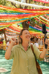 Vlogger traveler woman recording video on phone share via app travel vacation. Middle age woman influencer shooting social media stories on decorated street of Alfama district in Lisbon, Portugal