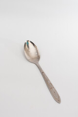 A worn metal spoon with a decorative handle, isolated on a clean white background, symbolizing...