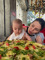 Mother and Baby Enjoying Pizza at a Restaurant