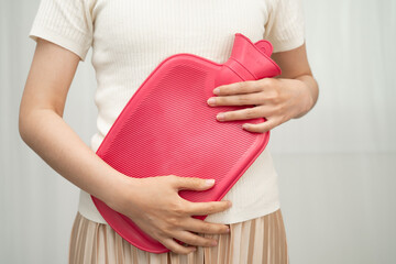 Woman using hot water bottle to relieve menstrual abdominal pain.