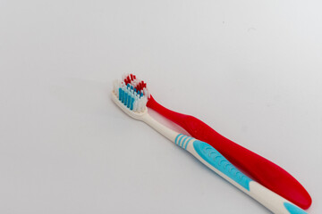A pair of toothbrushes, one red and one white, isolated on a clean white background, symbolizing...