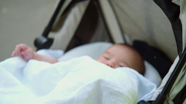 Little asian baby boy is lying outdoor in a stroller