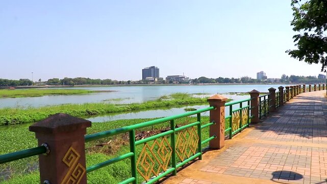 Lake with green tropical nature walking path blue sky Thailand.