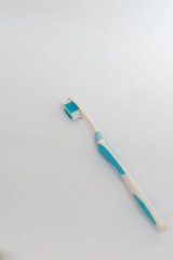 A white toothbrush with blue and red bristles, isolated on a clean white background, symbolizing...
