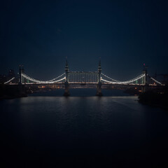 Fototapeta premium lluminated bridge at night reflecting on the water's surface in a tranquil urban setting