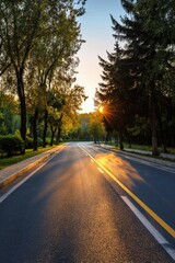 Obraz premium Asphalt road through park at sunset