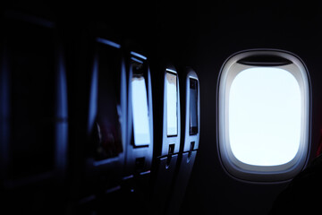 Airplane cabin interior with glowing window and empty seats