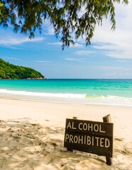Tropical beach scene with a wooden sign prohibiting alcohol