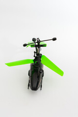 A black toy helicopter with bright green propellers, isolated on a clean white background,...