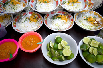 Soto Ayam, an Indonesian traditional chicken soup with lemon slices and chili sauces