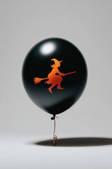 A black balloon with a simple an orange flat icon of a silhouette of Halloween ghost printed on it, isolated on a white background