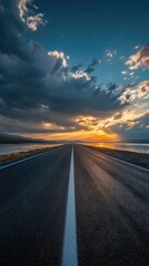 Fototapeta premium Asphalt road leading to a sunset over a lake