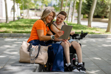 Volunteer helping disabled woman using tablet in park