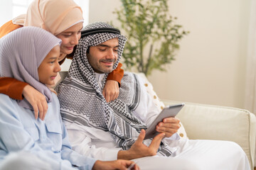 Muslim family learning online use tablet for homeschool education, daughter engaged in e-learning while parents guide with modern knowledge digital, online entertainment and muslim kids development