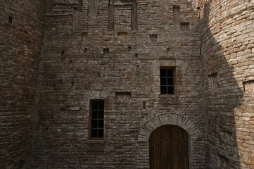 Medieval stone fortress facade with wooden door and windows, seamless 2D illustration for game background