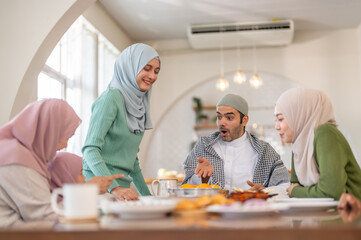 Muslim big family sharing traditional meal together around dining table wearing hijabs and kufi in cultural love, ramadan iftar celebration, eid al-fitr festive, halal meal gathering food culture