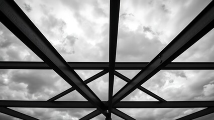 Steel beams forming geometric patterns against a cloudy sky, emphasizing industrial design.