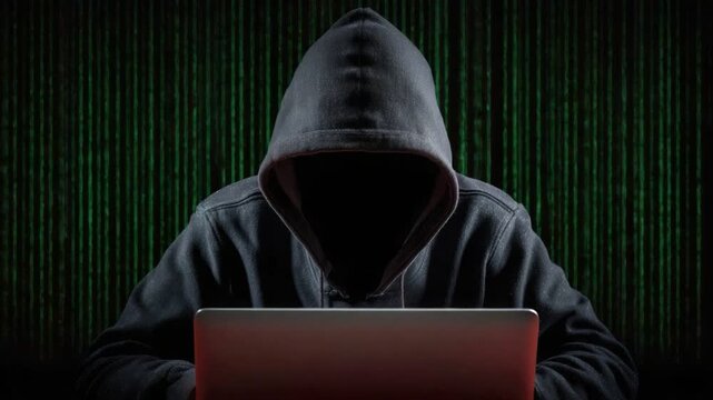 A mysterious hacker in a dark hoodie is focused on a laptop, surrounded by a backdrop of green binary code, symbolizing cybersecurity and digital secrecy.