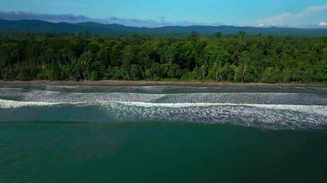 Untouched remote pristine coastline waves Cape Wom Papua New Guinea PNG aerial drone Madang Wewak Kavieng Vanimo Tufi sunny beach blue sky tranquil tropical shoreline East Sepik Province right slowly